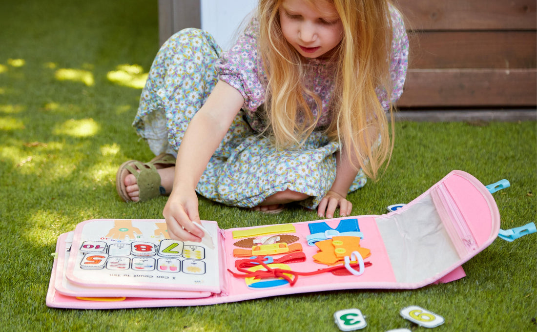 Toddler girl playing independently with My First Busy Board by Milleli number recognition page